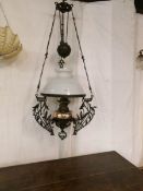 An Art Nouveau cast iron rise and fall oil lamp with brass font and original shade
