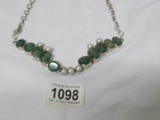 An emerald and pearl necklace set in silver