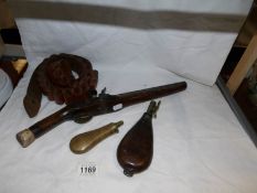 An Arabian flintlock pistol with inlaid silver decoration and wooden stock, a leather powder flask