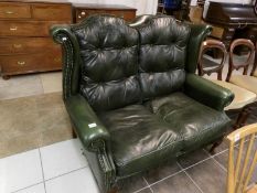 A 2 seat green leather wing back sofa