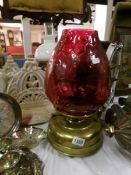 A brass oil lamp with cranberry glass shade