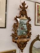A gilt framed mirror with shelf