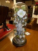 A Victorian bisque figurine with porcelain floral display under glass dome