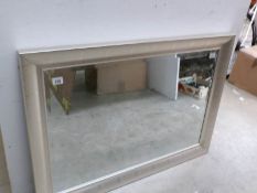 A bevel edged mirror in silver coloured frame