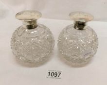 A pair of Edwardian cut glass globular and silver mounted scent bottles with mushroom hinged silver