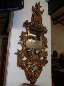 A gilt framed mirror with display shelf