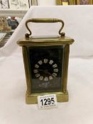 A brass carriage clock with black enamelled dial,