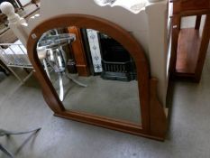 A wood framed arch topped over mantel mirror