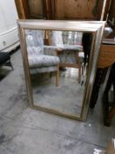 A bevel edged mirror in silver coloured frame