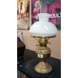 A brass oil lamp with opaque shade
