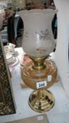 A brass oil lamp with frosted glass font and acid etched shade