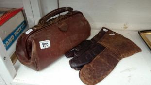 A leather Gladstone bag and a pair of vintage leather motorcycle gloves
