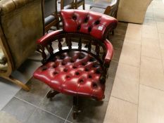 A deep red leather captain's chair (small piece of wood missing underneath