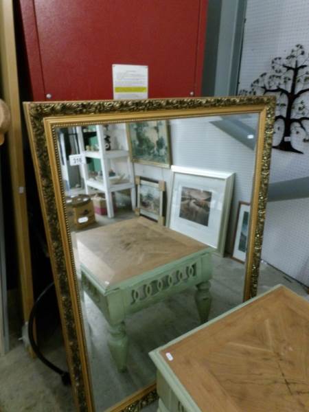 A large gilt framed mirror featuring Dahlia,