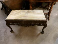 A marble topped dark wood coffee table on lion paw feet