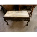 A marble topped dark wood coffee table on lion paw feet