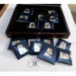 A collection of enamelled coins in wooden case