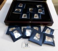 A collection of enamelled coins in wooden case