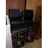 A pair of chrome bar stools with black seats