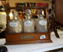 An oak 3 bottle tantalus complete with decanters and labels