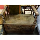 1920’s Oak Hall Bench, the hinged seat enclosing a chest, with raised side arms, on turned supports,