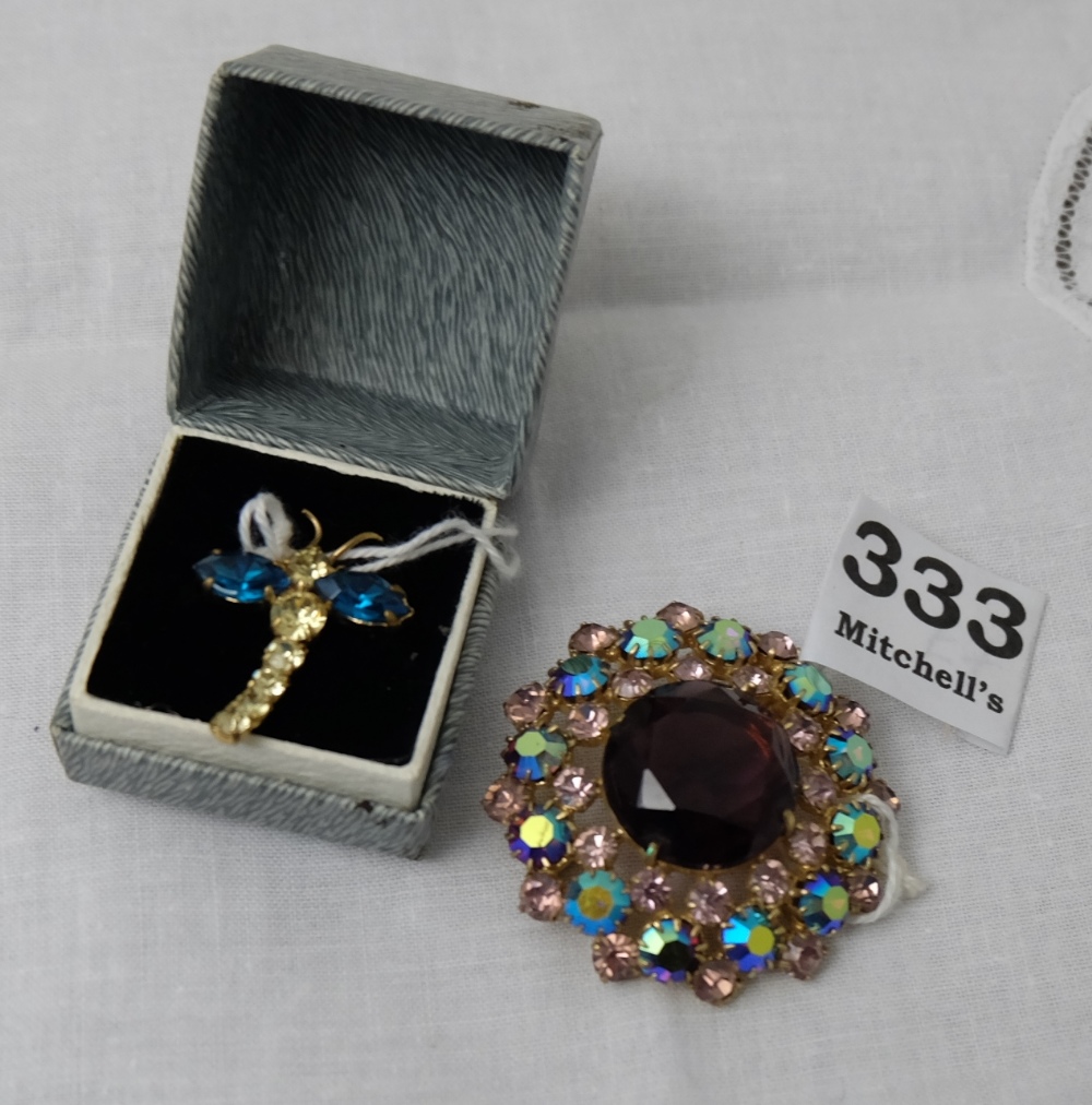 Two coloured dress brooches – 1 in the form of a dragonfly and 1 circular with amethyst centre paste