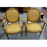 Matching Pair of carved wood Armchairs, painted gold, with gold floral covered padded backs and