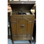 Record player in panelled oak cabinet, with hinged lid and cabinet enclosing a speaker, 29”w