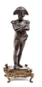 A bronze figure of Napoleon, wearing bicorne hat, standing with arms folded, his right foot