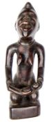 An early 20th century Kongo hardwood kneeling female maternity figure from the Congo, holding a