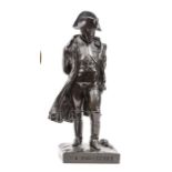 A bronzed brass figure of Napoleon, wearing bicorne hat and cloak, standing with hands folded behind