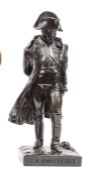 A bronzed brass figure of Napoleon, wearing bicorne hat and cloak, standing with hands folded behind
