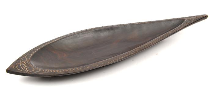 A New Guinea Massim teardrop shaped shallow dish, of dark hardwood, the rim decorated with border of