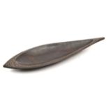 A New Guinea Massim teardrop shaped shallow dish, of dark hardwood, the rim decorated with border of