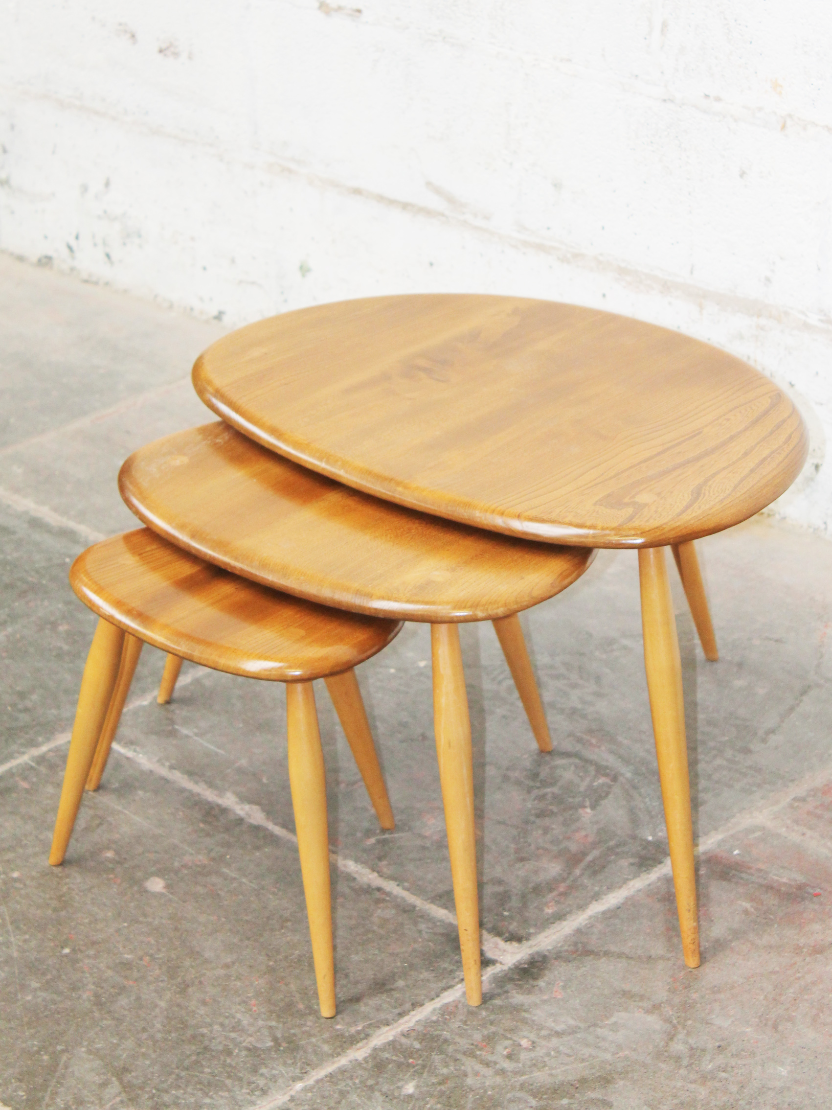 An Ercol light elm and beech nest of "Pebble" tables. Condition - good, general wear to include