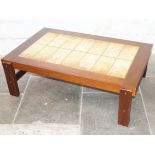 A 1970s coffee table having tiled top, the tiles decorated with cave painting inspired designs.