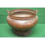 A large brass cooking pot having two hoo
