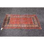 A red ground rug with blue and white pat