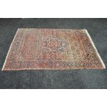 A red ground rug with black, blue and white pattern with end tassels - 84" x 58.