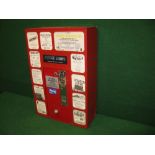 Red wall mounted metal stamp books vending machine, the eleven front windows containing local