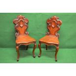 Pair of Victorian mahogany hall chairs with scrolled shield backs over solid seats with shaped