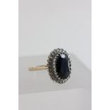 9ct Gold Ring set with large central oval sapphire and surrounded by small diamonds