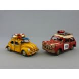 Two tin plate model cars in a red Mini and a yellow VW Beetle