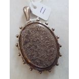 An oval Victorian silver locket one side crisply engraved with scrolls, hinged body