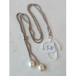 A fancy silver neck chain with a cultured pearl drop