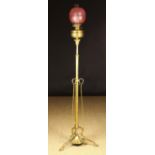 A Brass Oil Lamp with etched cranberry glass shade on a floor standing height adjustable Art