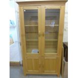 A modern oak display cabinet with two gl