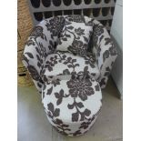 A modern tub armchair upholstered in foliate design with matching footstool