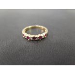 An 18ct gold ruby and diamond nine-stone ring - To the scalloped edge and plain band - Hallmarked