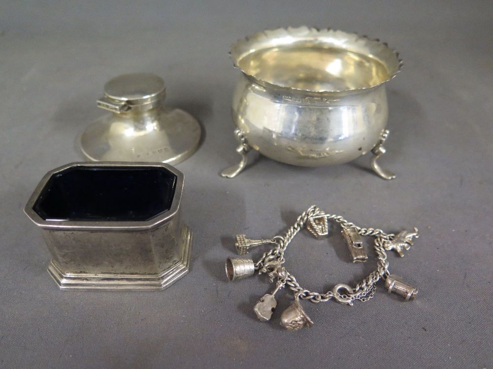 A silver hallmarked inkwell, sugar bowl with hallmark, a silver charm bracelet and a silver mustard